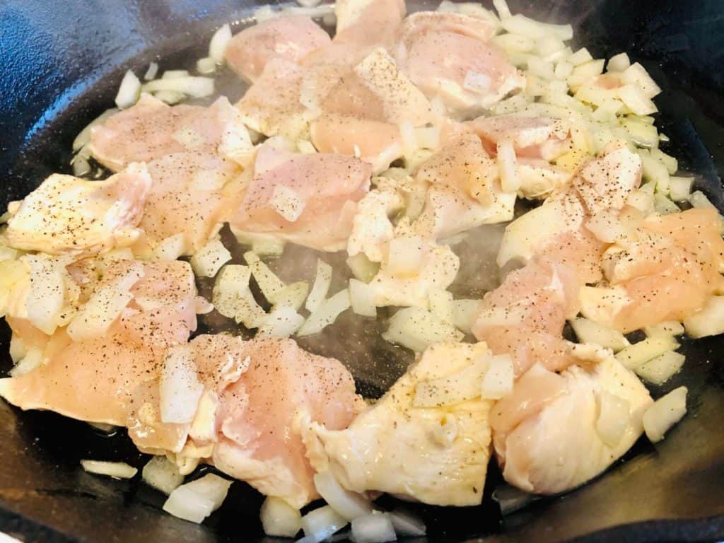 chicken cooking in skillet with onions